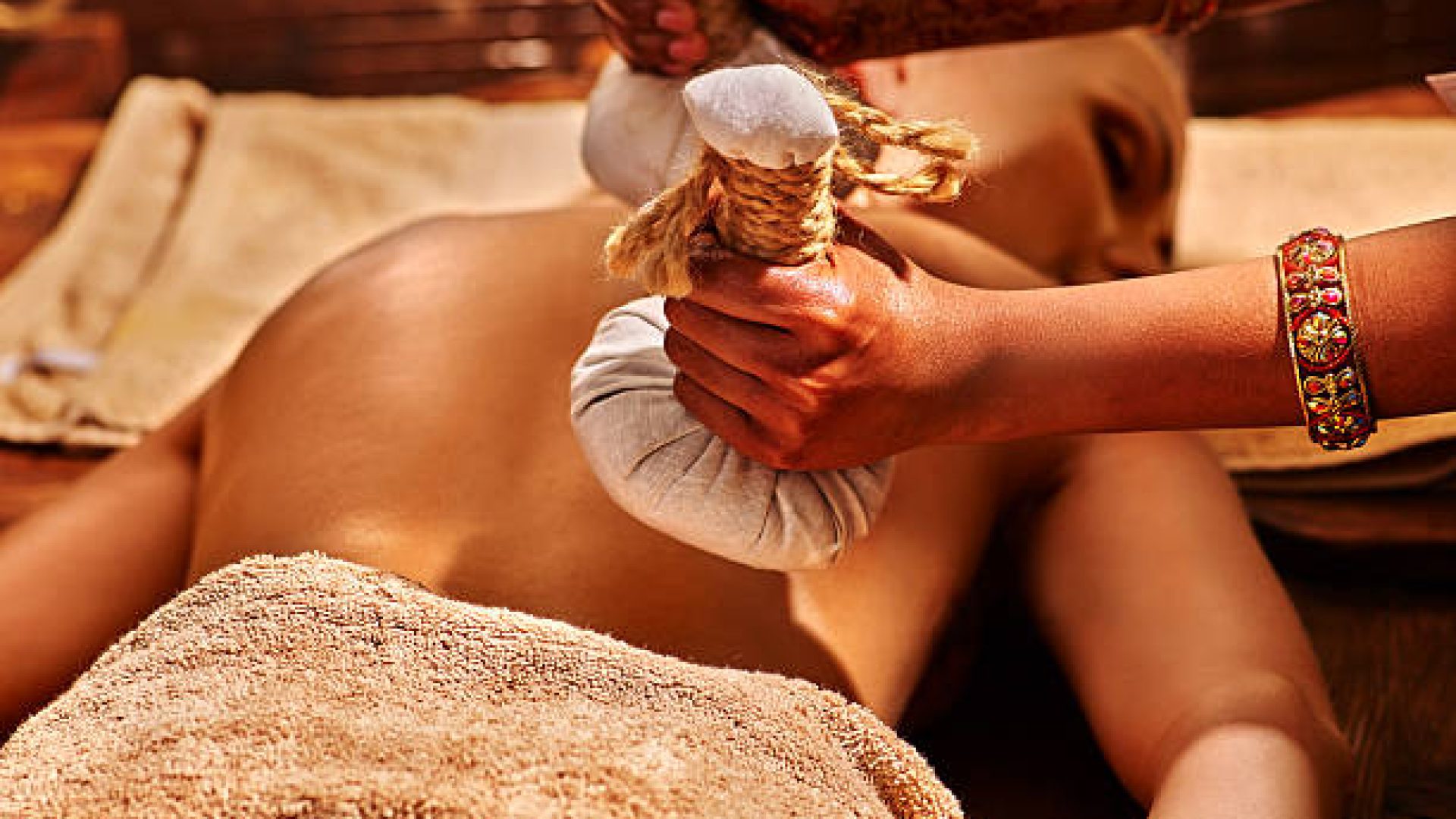 Woman having ayurvedic massage with back pouch of rice. Close up of exotic India massage.