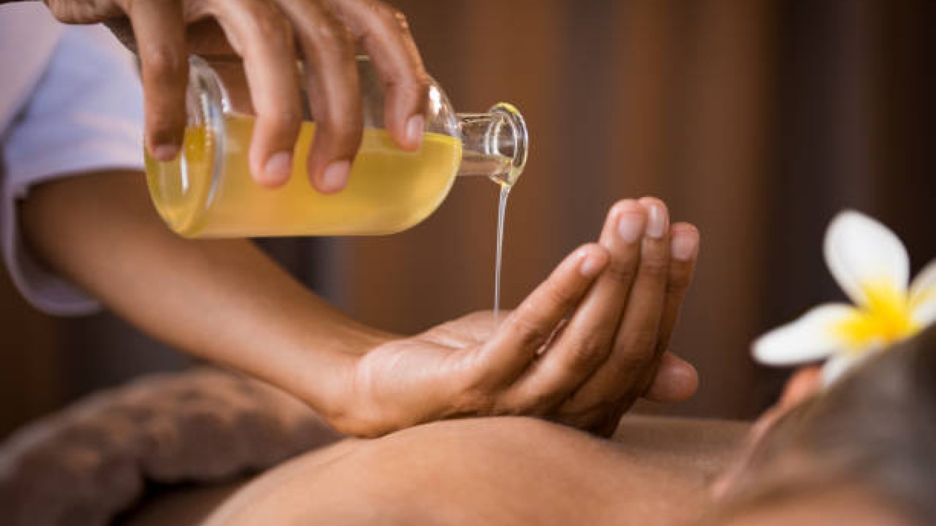 Closeup of masseur hands pouring aroma oil on woman back. Masseuse prepare to do oriental spa procedure for relaxing treatment. Therapist doing aromatherapy oil massage on woman body.